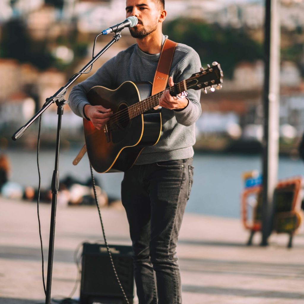 Man busking, singing and playing guitar outside